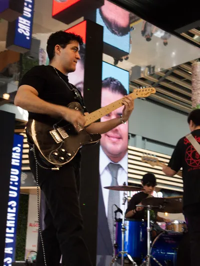 Guitarrista tocando con la batería al fondo